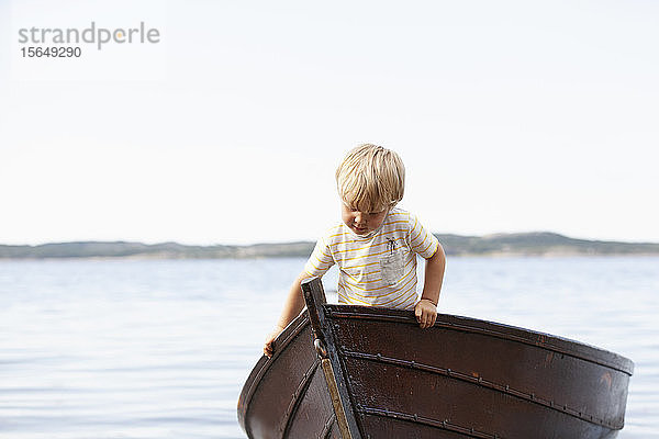 Junge spielt im Boot am Strand