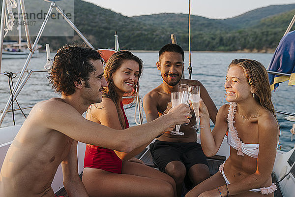 Freunde stoßen mit Champagner auf einem Segelboot an  Italien