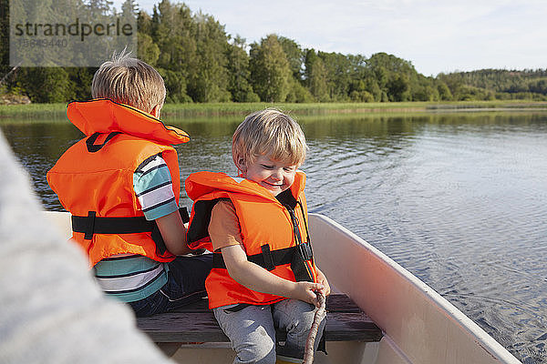 Erwachsener segelt mit Jungen auf einem Boot auf dem See  Finnland