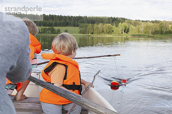 Erwachsener segelt mit Jungen auf einem Boot auf dem See  Finnland