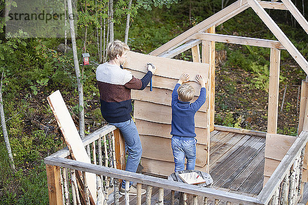 Vater und Sohn bauen gemeinsam Baumhaus im Garten