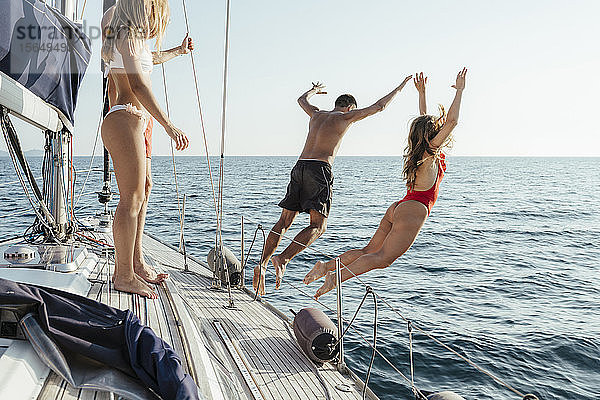Freunde springen vom Segelboot ins Meer  Italien