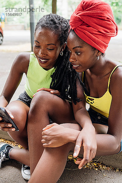 Freunde lesen Textnachricht auf Smartphone in der Stadt