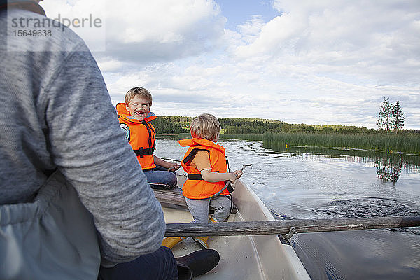 Erwachsener segelt mit Jungen auf einem Boot auf dem See  Finnland