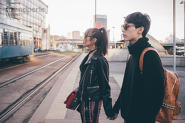 Junges Paar  das an den Straßenbahnschienen Händchen hält und wartet  Mailand  Italien