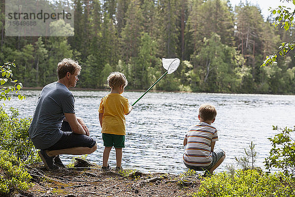 Vater und Söhne spielen mit dem Fischernetz am See  Finnland