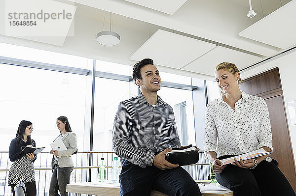 Geschäftsmann mit VR-Headset und Geschäftsfrau im Gespräch im Büro  Kollegen im Hintergrund