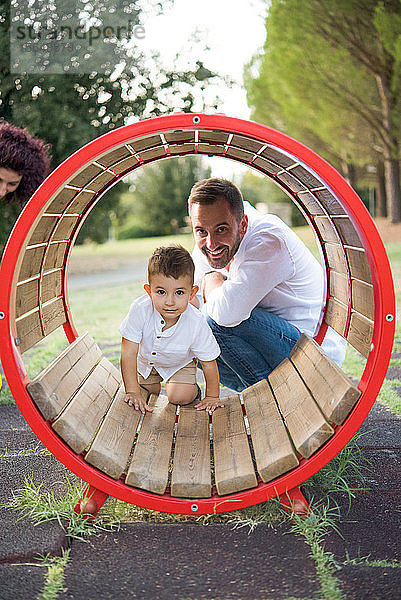 Vater beobachtet Sohn beim Rundschaukeln im Park