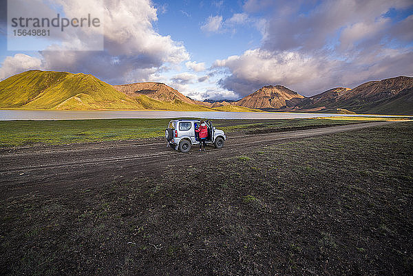 Reisende  die neben dem Fahrzeug eine malerische Aussicht genießt  Landmannalaugar  Hochland  Island