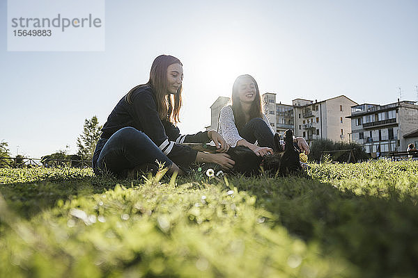 Schwestern spielen mit Hund im Park