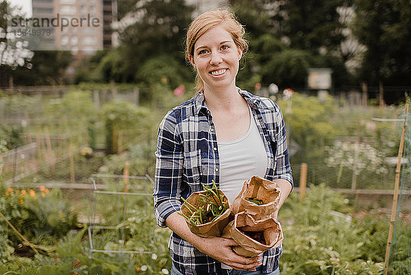 Frau trägt braune Säcke mit Gemüse im Schrebergarten