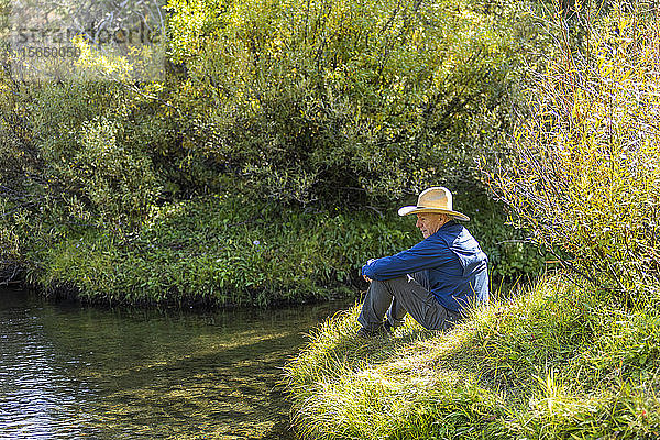 Mann sitzt im Gras bei Dampf in Stanley  Idaho  USA
