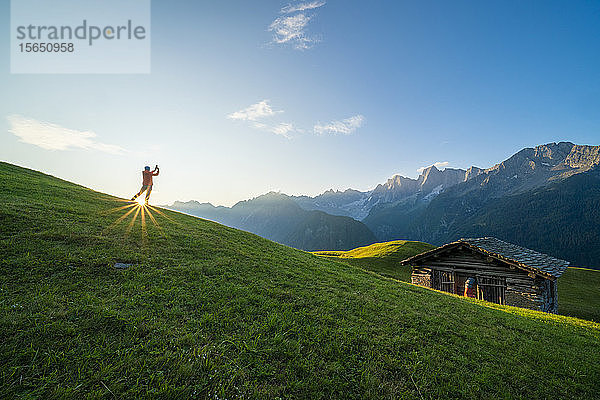 Von der Sonne beleuchteter Mann beim Fotografieren von Piz Badile und Cengalo  Tombal  Soglio  Bergell  Kanton Graubünden  Schweiz