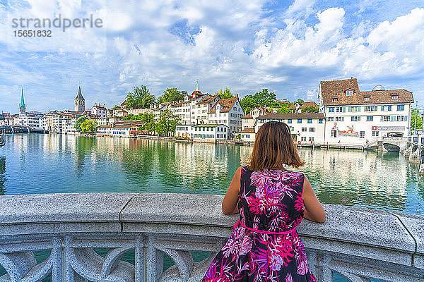 Rückansicht einer Frau  die auf einer Terrasse über der Limmat sitzt und die alten Gebäude des Lindenhofs bewundert  Zürich  Schweiz