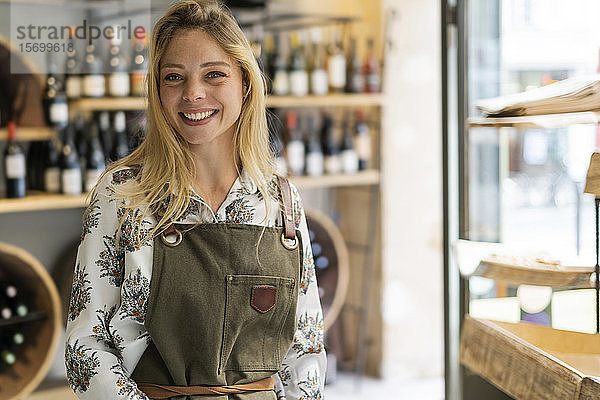 Lächelnde junge Frau im Weinladen stehend
