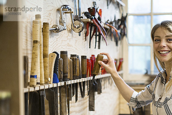 Frau hält Handwerkzeug in einer Werkstatt