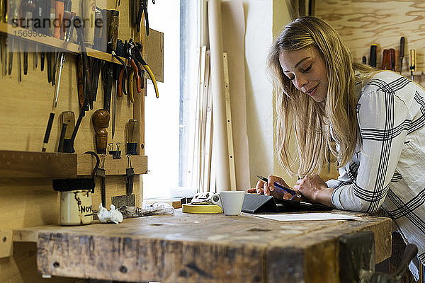 Frau benutzt digitales Tablet in einer Werkstatt