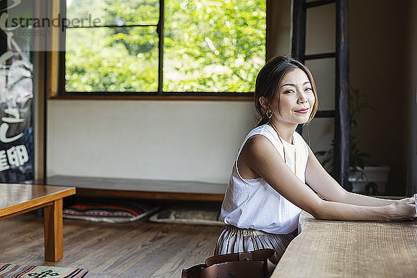 Lächelnde Japanerin  die an einem Tisch in einem japanischen Restaurant sitzt.