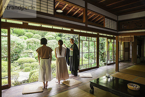 Buddhistischer Priester und zwei japanische Frauen stehen im buddhistischen Tempel.
