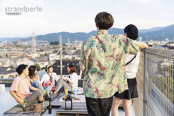 Gruppe junger japanischer Männer und Frauen auf einem Dach in einer städtischen Umgebung.