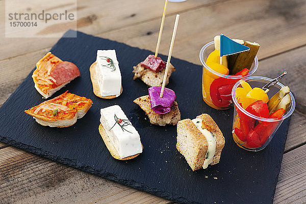 Hochwinkel-Nahaufnahme einer Auswahl von Sandwiches und frischem Gemüse auf einer Schiefertafel.
