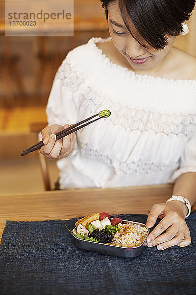 Japanische Frauen essen mit Stäbchen in einem vegetarischen Café.