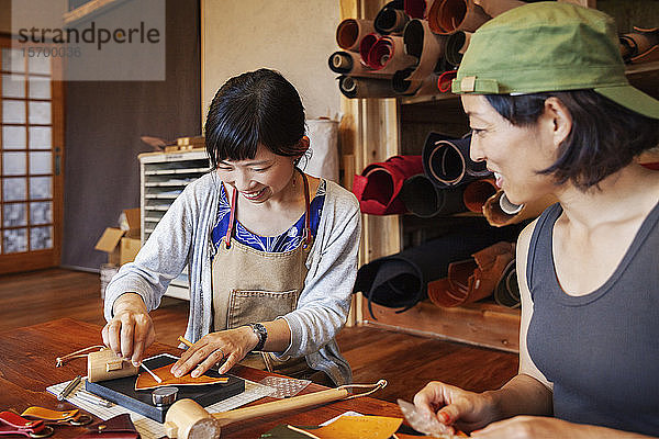 Zwei Japanerinnen  die an einem Tisch sitzen und in einem Ledergeschäft arbeiten.