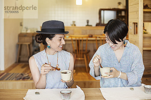 Zwei lächelnde Japanerinnen beim Essen in einem vegetarischen Café.