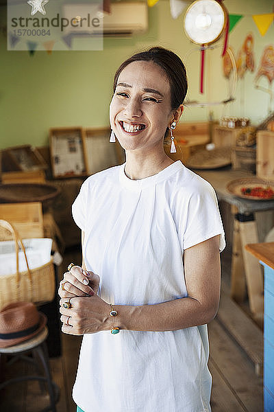 Lächelnde Japanerin steht in einem Bauernladen und schaut in die Kamera.