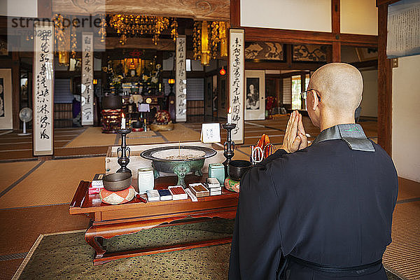 Buddhistischer Priester im buddhistischen Tempel kniend und betend.
