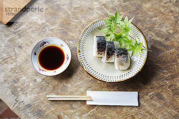 Hochwinkelaufnahme eines Sushi-Tellers und einer Schüssel Sojasauce auf einem Tisch in einem japanischen Restaurant.