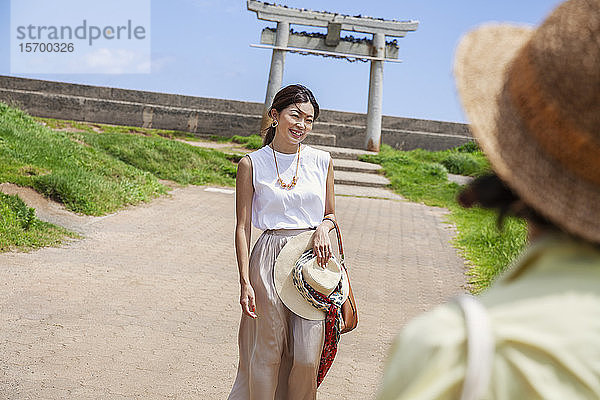 Zwei Japanerinnen mit Hüten stehen auf einem Weg und fotografieren.