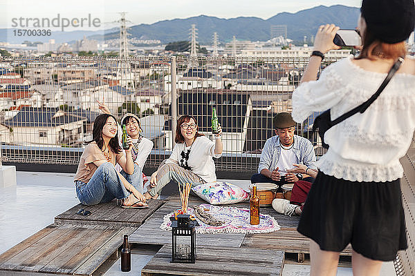 Lächelnde Gruppe junger japanischer Männer und Frauen auf einem Dach in einer städtischen Umgebung.