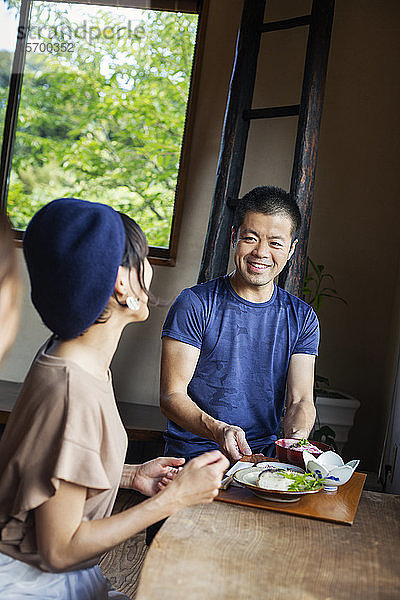 Kellner  der zwei Japanerinnen bedient  die an einem Tisch in einem japanischen Restaurant sitzen.