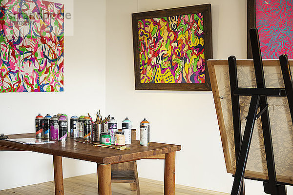 Innenansicht oder Kunstgalerie mit Atelierraum  Staffeleien und Dosen mit Sprühfarbe auf einem Tisch.