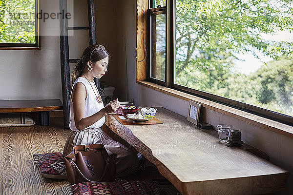 Japanerin  die an einem Tisch in einem japanischen Restaurant sitzt und isst.