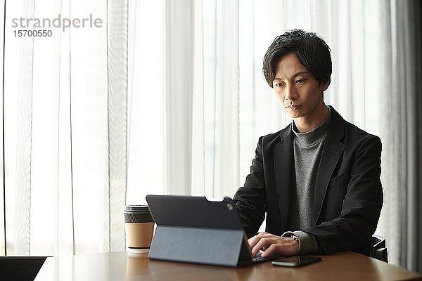 Junger japanischer Geschäftsmann in einem Cafe