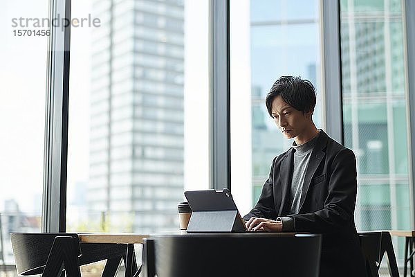 Junger japanischer Geschäftsmann in einem Cafe