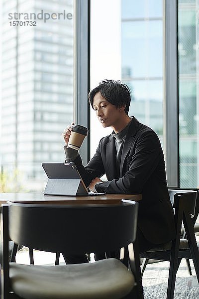 Junger japanischer Geschäftsmann in einem Cafe