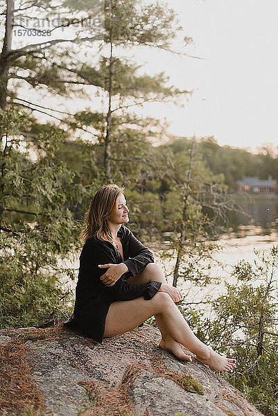 Frau entspannt sich auf einem Felsbrocken am See  Bobcaygeon  Ontario  Kanada