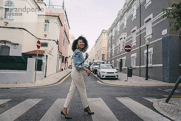 Porträt glückliche  stilvolle Frau beim Überqueren der Stadtstraße