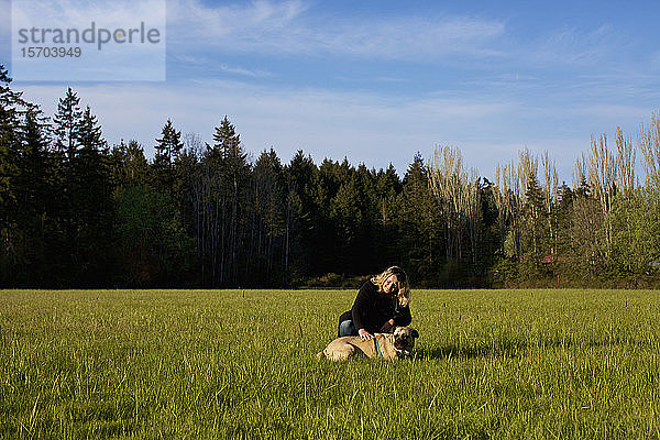 Frau mit Hund in einem sonnigen  ländlichen Feld