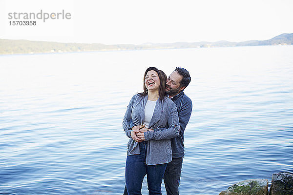 Glückliches  zärtliches Paar lachend und umarmend am See