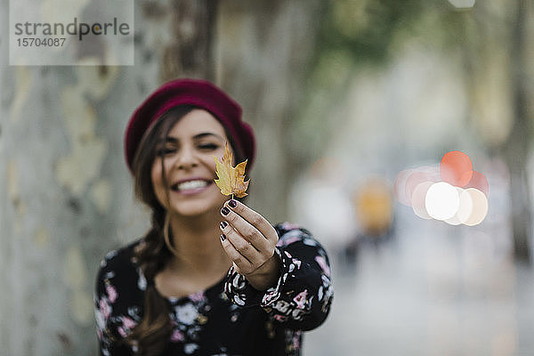 Porträt glückliche junge Frau hält Herbstblatt