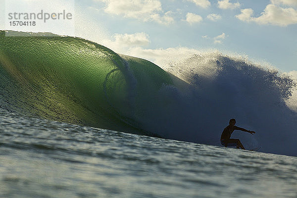 Silhouettierter männlicher Surfer auf einer Meereswelle