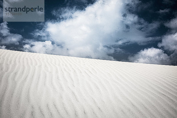 Muster über Sanddüne unter Wolken am Himmel