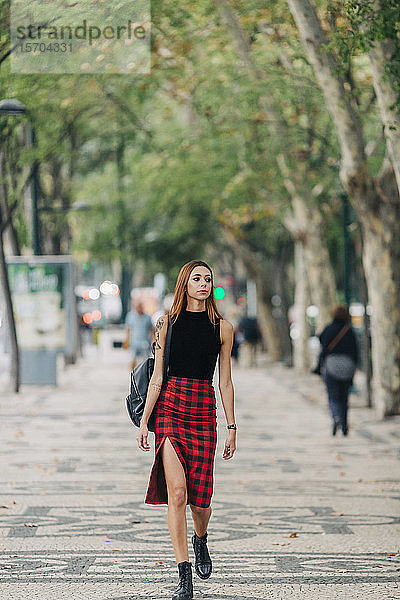 Stilvolle junge Frau geht im Stadtpark spazieren