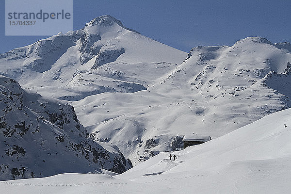 Menschen gehen zu einer Hütte auf einem abgelegenen  schneebedeckten Berg  Vals  Kanton Graubünden  Schweiz