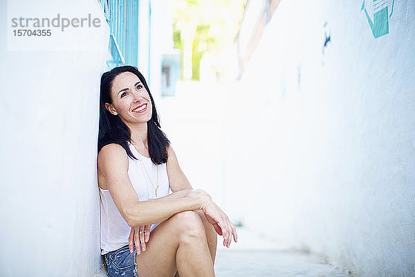 Porträt einer lächelnden  selbstbewussten Frau  die sich in einer Sommerallee entspannt
