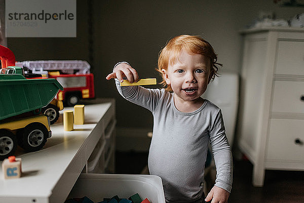 Kleinkind spielt mit Spielzeugklötzen im Wohnzimmer